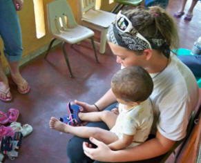 Sam helps malnourished boy try on some new flip flops