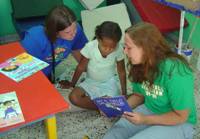 Courtney & Erin read a donated Spanish book to a child